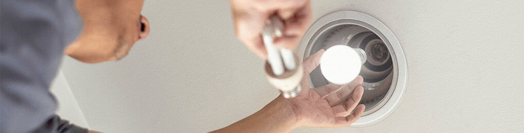 electrician replacing a ceiling lightbulb