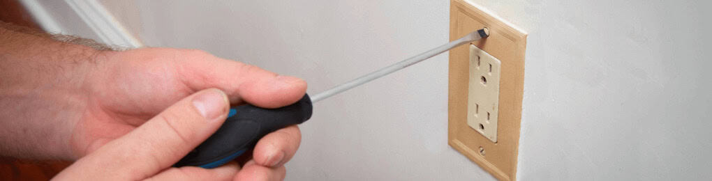 person using a screwdriver to replace an electrical outlet